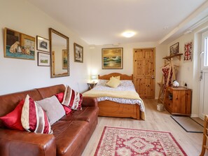 Quarto com cama de madeira, sofá de couro e guarda-roupa de madeira.
