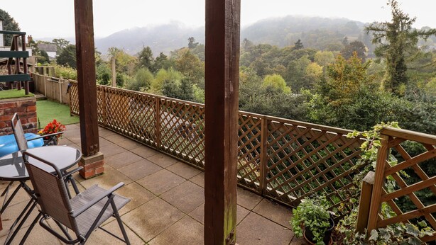 Un patio cubierto con vista a una ladera boscosa.