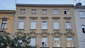 A multi-story building with a symmetrical facade, featuring evenly spaced windows and decorative elements around the entrance. - Charming 1-bed Apartment in Zagreb (Zagreb)