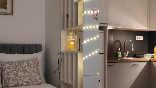 A bedroom with a large bed, a nightstand, a dresser, and a built-in wardrobe with lights. - Charming 1-bed Apartment in Zagreb (Zagreb)