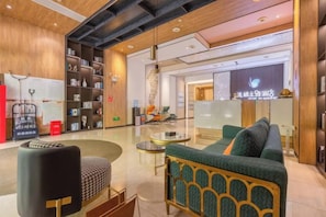 Eine moderne Lobby mit einer Rezeption, einer Sitzecke und einem Bücherregal.