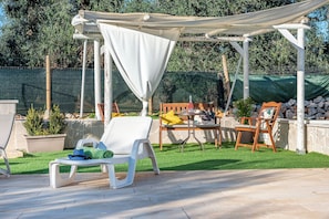 An outdoor patio with a pergola, seating area, and potted plants.