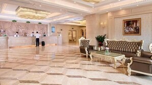 Eine Hotelhalle mit Empfangstresen, Sitzgelegenheiten und einem Chandelier.