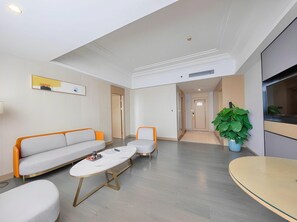 Uma sala de estar moderna com um sofá, duas poltronas, uma mesa de centro e uma televisão.