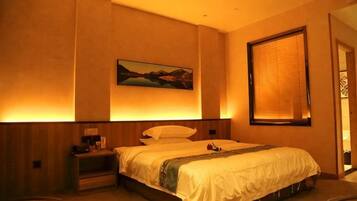 A hotel room with a bed, bedside table, and a painting on the wall.