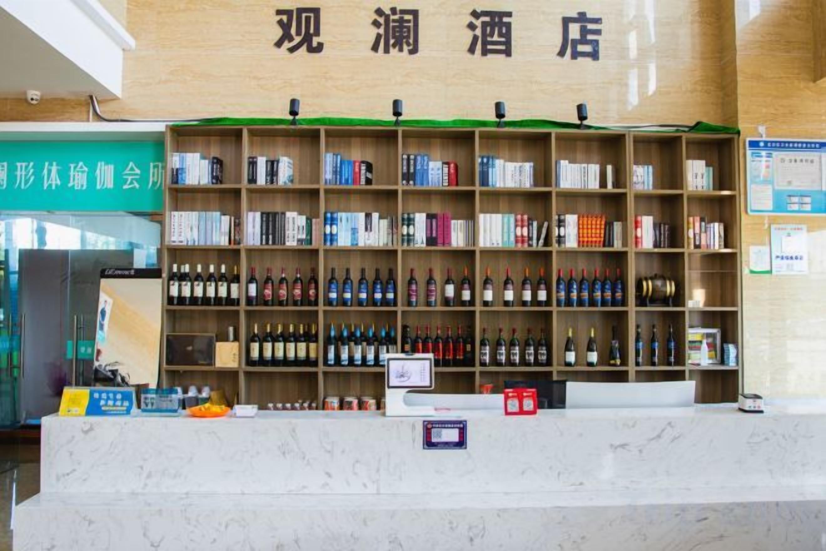 A hotel reception area with a marble counter, shelves of alcohol, and a sign above indicating the hotel's name.