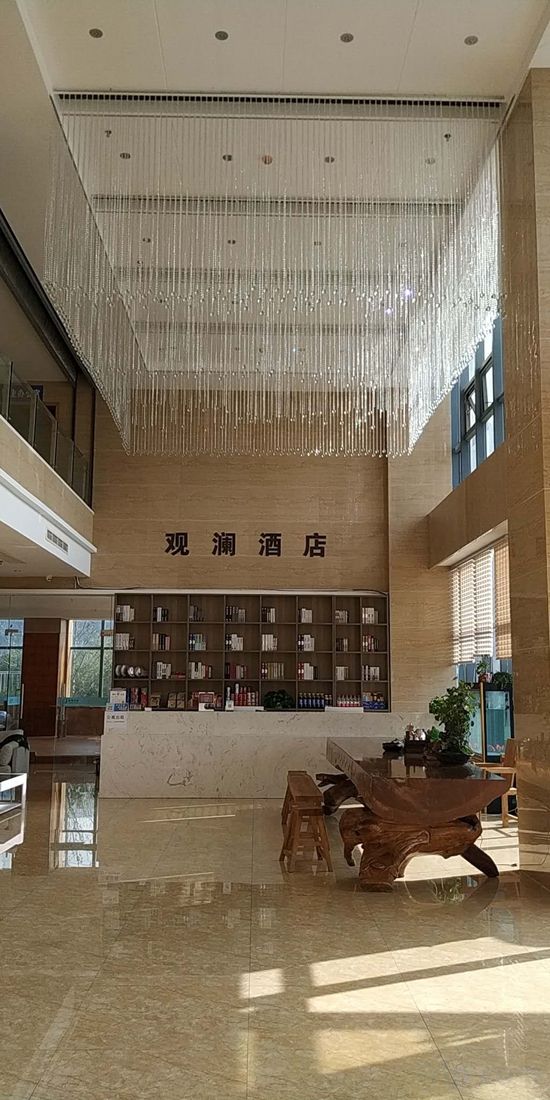 Een hotel lobby met een hoge plafond, een houten receptiebalie en een grote boekenkast.