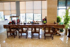 A long wooden table with chairs in a room with large windows and a tiled floor. - Guanlan Hotel (Ningbo)