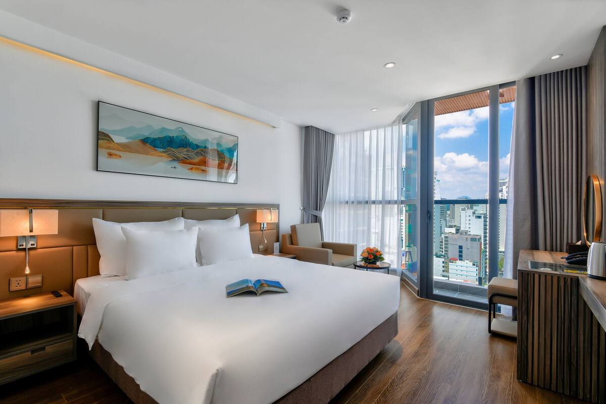 Una habitación de hotel moderna con una cama grande, un escritorio y vistas a la ciudad.