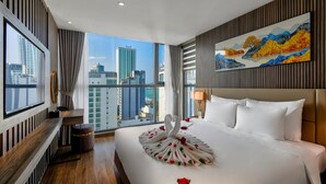 Une chambre d’hôtel moderne avec un grand lit, une console en bois, un tableau et une vue sur la ville.