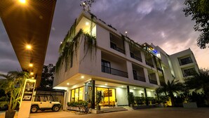 Un hotel de varios pisos con fachada blanca, balcones e ingreso bien iluminado.
