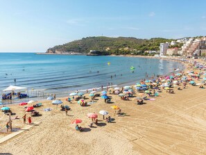 Una playa con muchas sombrillas, sillas de playa y gente disfrutando del agua.