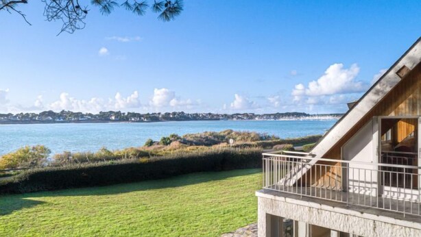 Una proprietà sul lungomare con patio in pietra, terrazza in legno e vista mare.