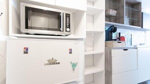 Eine Küche mit Einbau-Mikrowelle, Kühlschrank und weißen Schränken.