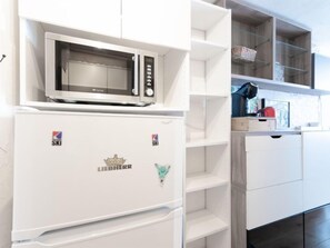 A kitchen with a built-in microwave, a refrigerator, and white cabinetry.