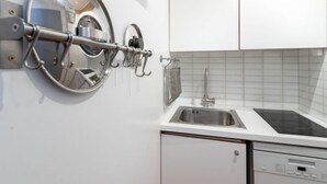 Eine Küche mit weißen Schränken, einer Edelstahl-Spüle und einem an der Wand befestigten Geschirrgestell.