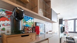 Eine moderne Küche mit Kaffeemaschine, rotem Wasserkocher und Holzschrank.