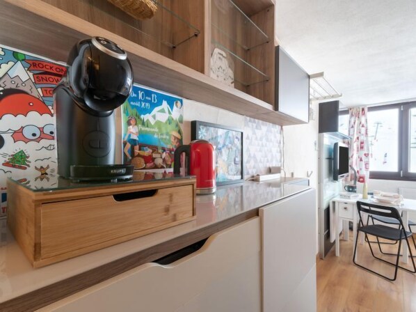 A modern kitchen with a coffee maker, a red kettle, and a wooden cabinet. - Palafour (Le Lac) by Interhome (Tignes)