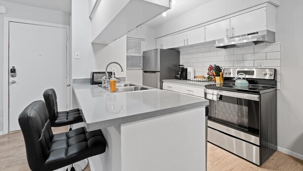A modern kitchen with a central island, stainless steel appliances, and white cabinetry.