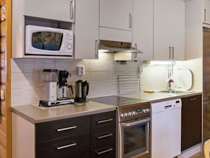 A modern kitchen with a microwave, coffee maker, and dishwasher.