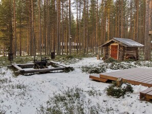 Une cabane entourée d’une forêt enneigée.