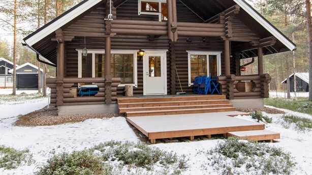 Een vakantiehuisje met een veranda, schoorsteen en een trap die naar de ingang leidt.