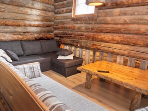 A log cabin interior with a sofa, ottoman, and wooden table. - Agenttimajat 1 by Interhome (Kuusamo)