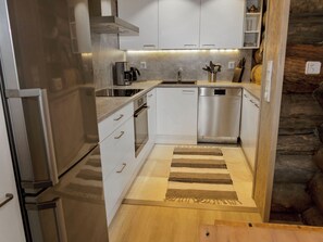 A compact kitchen with white cabinets, stainless steel appliances, and a wooden floor. - Agenttimajat 1 by Interhome (Kuusamo)