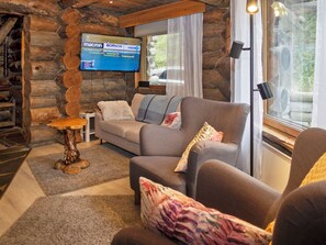 Ein gemütliches Wohnzimmer mit Steinwand, Flachbildfernseher, Sofa und Couchtisch.