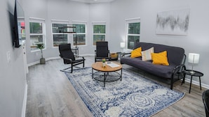 A modern living room with a grey sofa, black chairs, a coffee table, and a blue patterned rug.