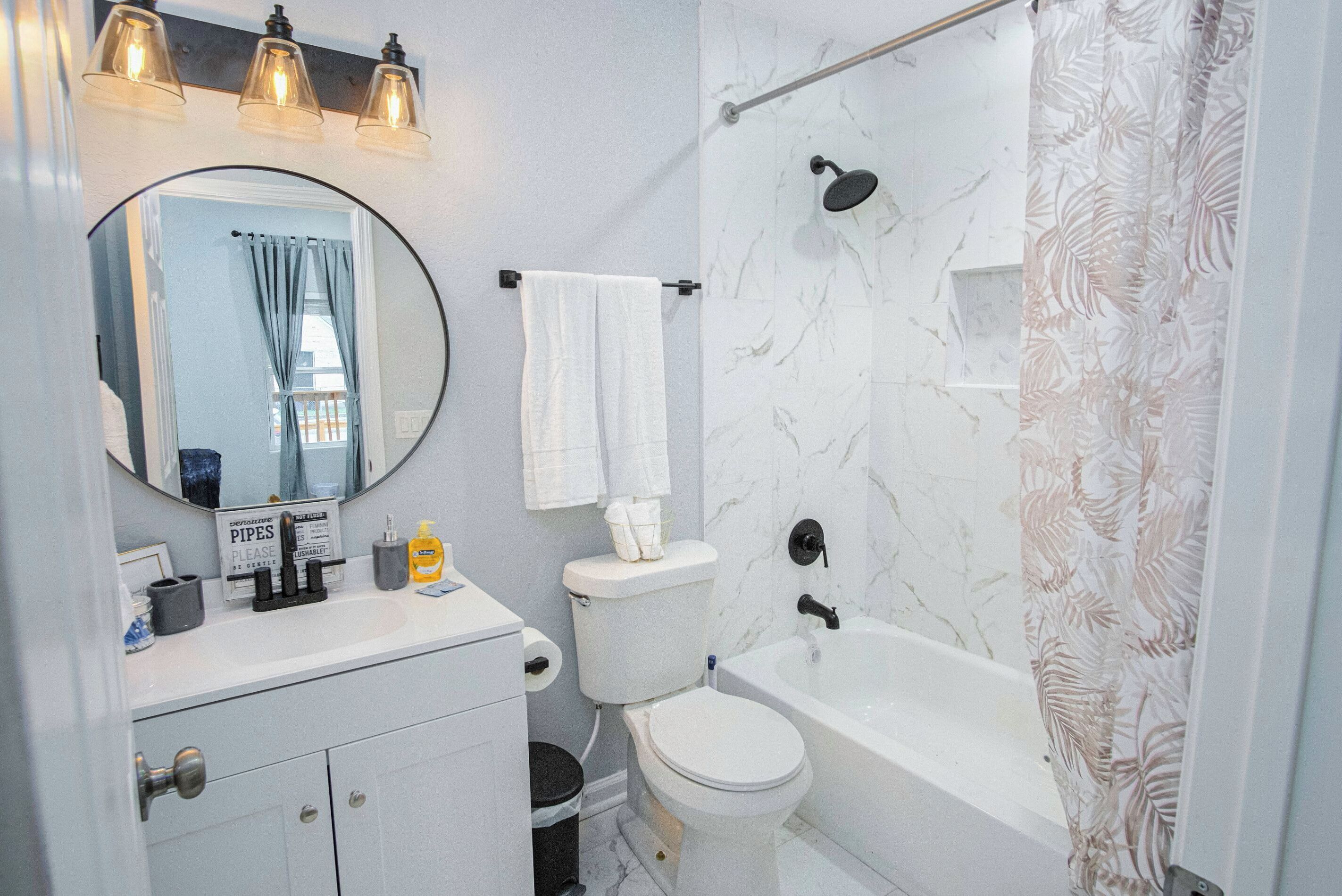 Ein Badezimmer mit Toilette, Waschbecken, Spiegel und Badewanne.