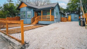 A two-story blue house with a porch and wooden steps leading to the front door.