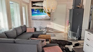 A modern living room with a grey sectional sofa, a flat-screen TV, a unique chandelier, and a cowhide rug. - Willa kiiruna by Interhome (Enontekiö)