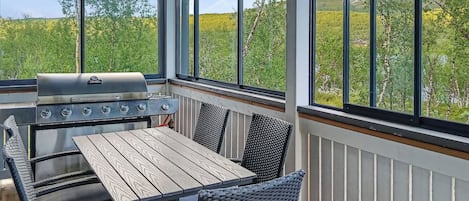 An outdoor patio with a grill, table, and chairs.