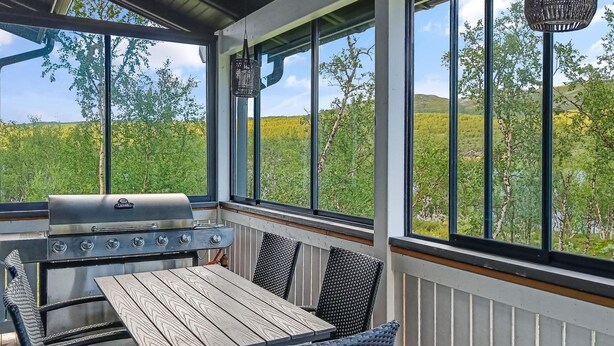 An outdoor patio with a grill, wooden table, and wicker chairs. - Willa kiiruna by Interhome (Enontekiö)