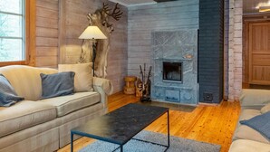 A cozy living room with a fireplace, wooden walls, and a sofa.