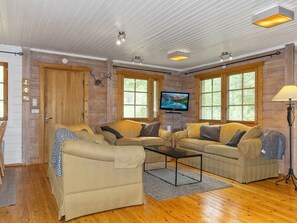 A cozy living room with two sofas, a coffee table, and a TV on the wall.