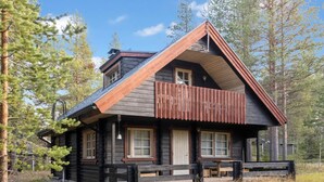 A cabin with a sloped roof, a balcony, and a front porch with benches.