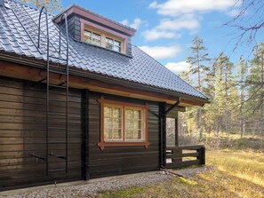 A cabin with a sloped roof, a window with a wooden frame, and a wooden door.