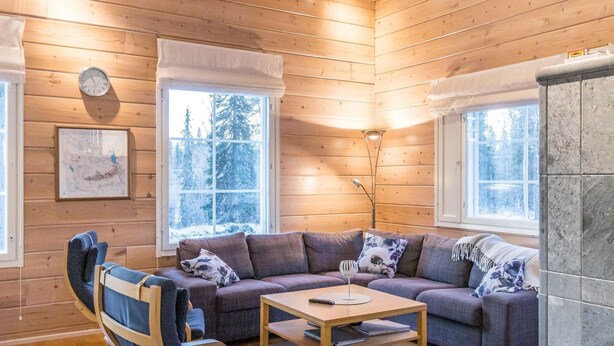 Een knus cabin interieur met houten details, een bank, een bijzettafeltje en een stoel.