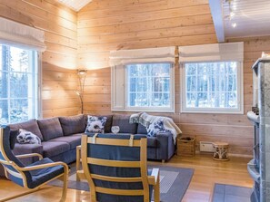 Interior acogedor de una cabaña con detalles de madera, un sofá modular, un sillón y una chimenea.