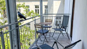Ein Balkon mit Metallgeländern, einem Holzstuhl und einem Klappstuhl.