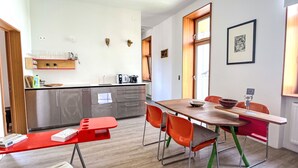Eine moderne Küche mit Edelstahlgeräten, einem Holzespeisetisch mit orangefarbenen Stühlen und einer roten Bank.