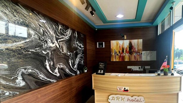 Zona de recepción de hotel con pared de mármol, mostrador de madera y un cuadro en la parte superior.