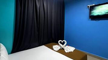 Una habitación de hotel con una cama, un televisor montado en la pared y una cortina.