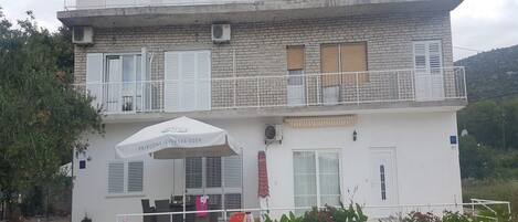 Um edifício de dois andares com varanda, área de estar coberta ao ar livre e uma placa indicando que é um restaurante.