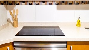 A kitchen with a black induction cooktop, wooden utensils, and a yellow bottle of oil on the counter. - Apartment in Albacete center (Albacete)