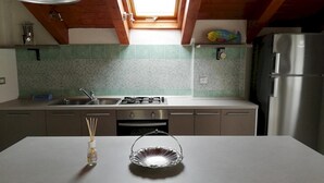 A modern kitchen with a skylight, stainless steel appliances, and a tiled backsplash. - San Lazzaro 81 Mansarda (Andora)
