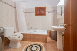 Een badkamer met toilet, bad en wastafel.