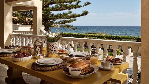 Une table de petit-déjeuner avec divers plats et une vue sur la mer.